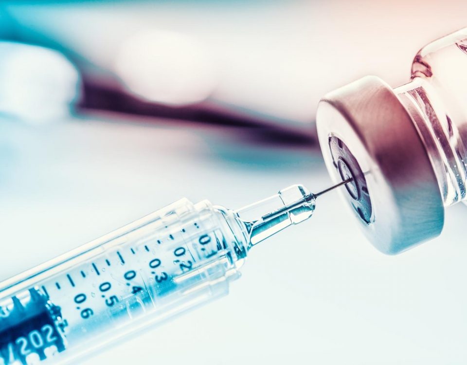 zdjęcie szczepionki i strzykawki na niebiesko-różowym tle